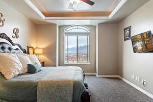 Bedroom featuring a raised ceiling, crown molding, carpet, and a ceiling fan