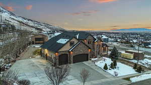 View of front facade featuring stucco siding, driveway, stone siding, a residential view, and a mountain view