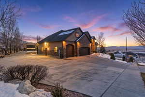 View of front facade featuring stone siding, concrete driveway, stucco siding, and an attached garage