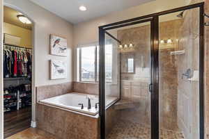 Full bathroom with a stall shower, a walk in closet, a bath, and recessed lighting