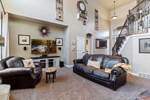 Living area featuring arched walkways, carpet floors, and a high ceiling