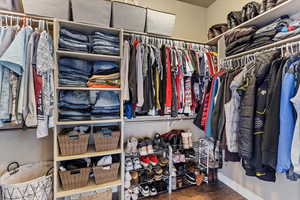 Walk in closet with dark wood-style floors