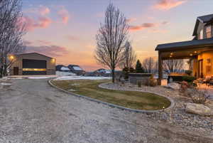 View of yard with an outdoor structure, a garage, a hot tub, and gravel driveway