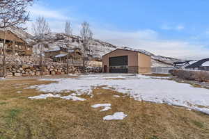Snowy yard featuring an outdoor structure, a mountain view, and a detached garage