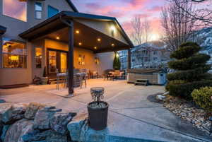 Patio terrace at dusk featuring a hot tub and a patio area