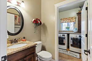 Half bathroom with washer and dryer, vanity, and light tile patterned flooring