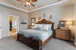 Bedroom featuring carpet, a raised ceiling, a ceiling fan, and ensuite bathroom