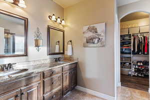 Full bathroom with a walk in closet and double vanity