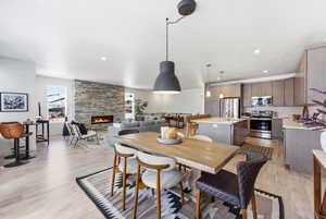 Dining space with light wood-type flooring, a stone fireplace, and recessed lighting