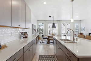 Kitchen with pendant lighting, light wood finished floors, light stone counters, stainless steel dishwasher, and a textured ceiling