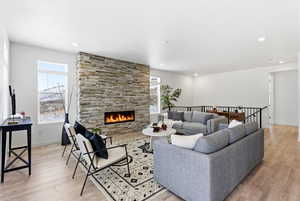 Living area featuring light wood-style floors and a stone fireplace