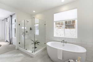 Bathroom featuring a shower stall, a freestanding bath, tile walls, and a wainscoted wall
