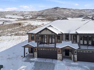 View of front of property with a garage, stone siding, a mountain view, and board and batten siding