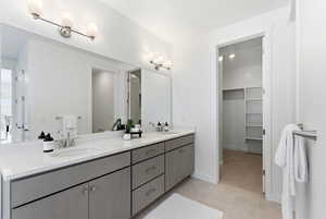 Full bath with double vanity, a spacious closet, and light tile patterned floors