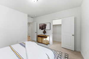 Bedroom with a spacious closet and light carpet