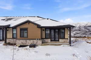 View of front of home with stone siding, french doors, and a mountain view