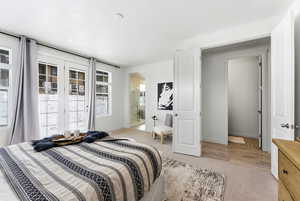 Bedroom with light colored carpet, access to exterior, and connected bathroom