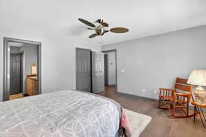 Bedroom with light wood finished floors, connected bathroom, a ceiling fan, and a closet