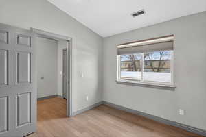 Unfurnished bedroom featuring vaulted ceiling and light wood-style flooring