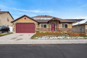 View of front of house featuring roof mounted solar panels, an attached garage, driveway, stucco siding, and a shingled roof