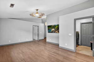 Unfurnished room with light wood finished floors, lofted ceiling, and washer / dryer