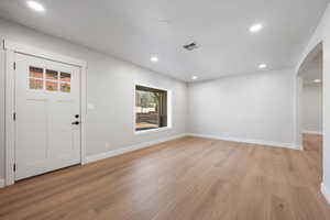 Foyer entrance featuring light wood-style flooring, recessed lighting, and arched walkways
