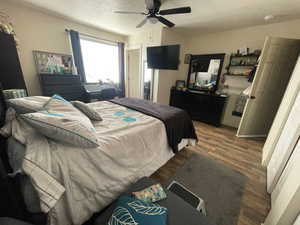 Bedroom with wood finished floors, ceiling fan, and a textured ceiling
