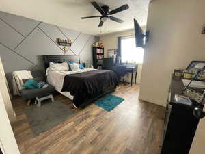 Bedroom with wood finished floors, a ceiling fan, and a textured ceiling