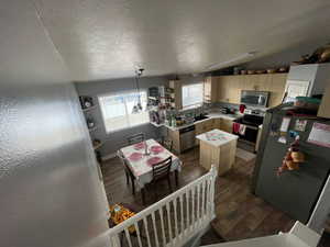 Kitchen featuring stainless steel appliances, light wood finish cabinetry, light countertops, and dark wood-style floors