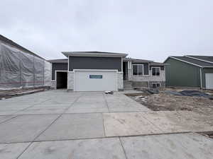 View of front of house featuring a garage, driveway, and stone siding