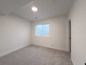Empty room featuring light colored carpet and baseboards