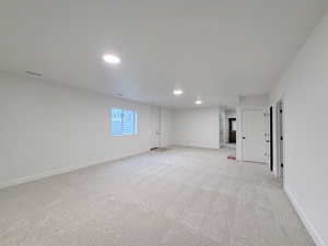 Empty room with light colored carpet and recessed lighting