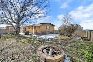 Back of house with a fire pit, a fenced backyard, a patio area, and brick siding