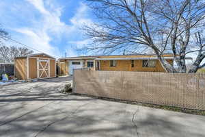 View of front facade featuring a storage shed, a fenced front yard, concrete driveway, and brick siding