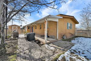 View of property exterior with a gate, brick siding, a wooden deck, and a patio area