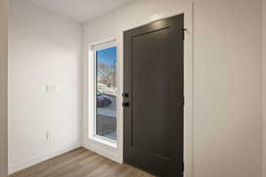 Doorway to outside with wood finished floors and baseboards