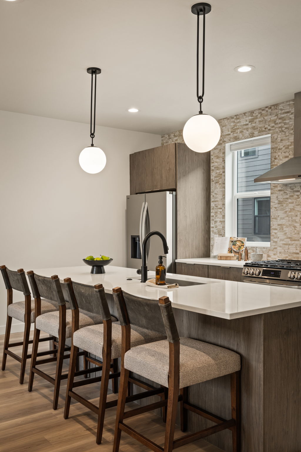 Kitchen with a breakfast bar, decorative light fixtures, stainless steel appliances, and dark wood-type flooring
