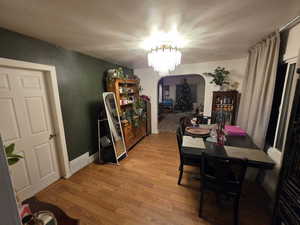 Dining area featuring arched walkways, a chandelier, and wood finished floors