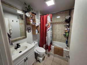 Bathroom featuring vanity, shower / bath combo with shower curtain, and light tile patterned flooring