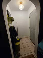 Mudroom with arched walkways and light tile patterned floors
