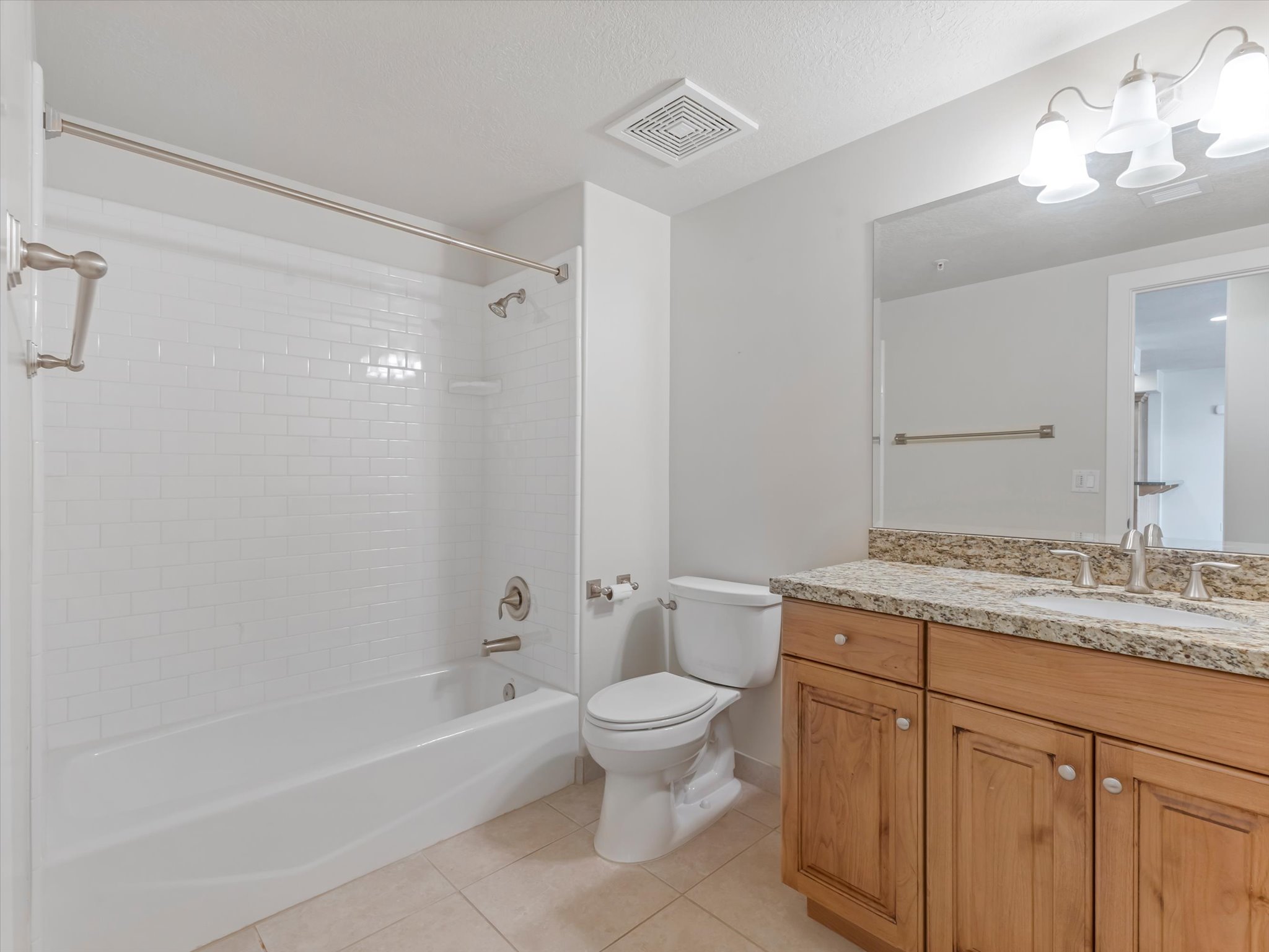 Bathroom featuring vanity, light tile patterned flooring, shower / washtub combination, hanging lights, and a textured ceiling