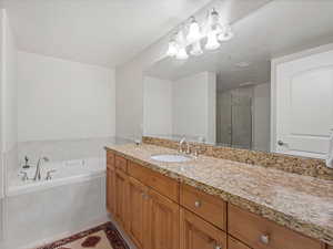 Master bathroom featuring a stall shower, vanity, a garden tub, a textured ceiling, and light tile patterned floors.
