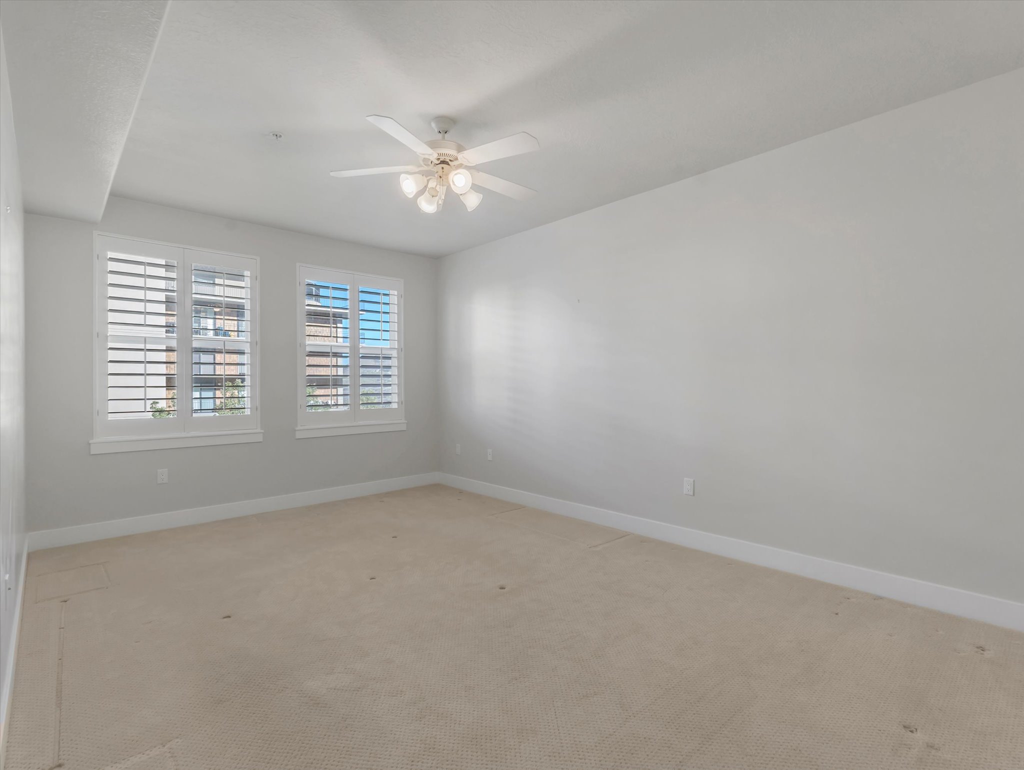 Empty room with a ceiling fan and light carpet