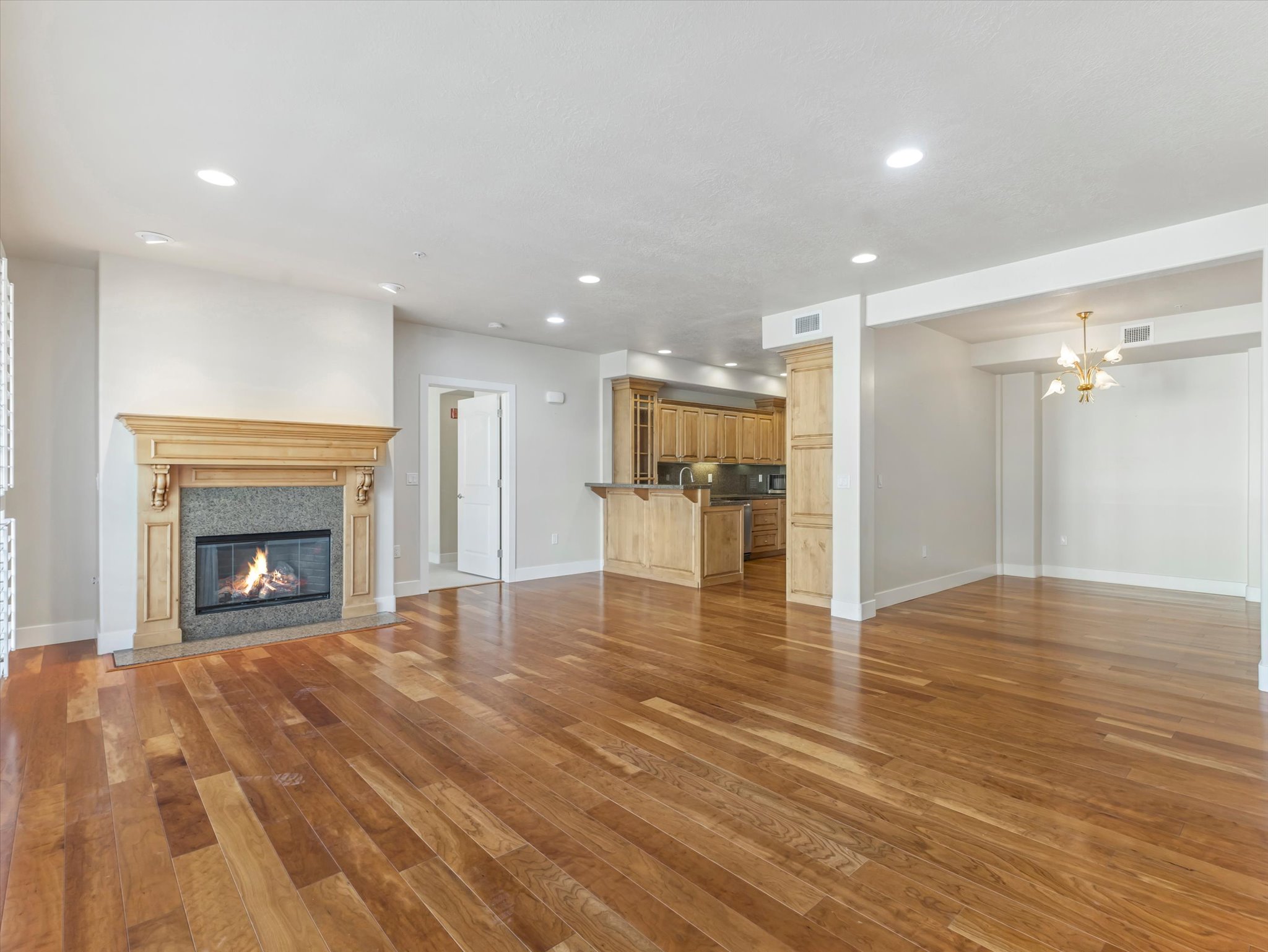 Unfurnished living room featuring light wood-style flooring, a high end fireplace, and suspended lighting