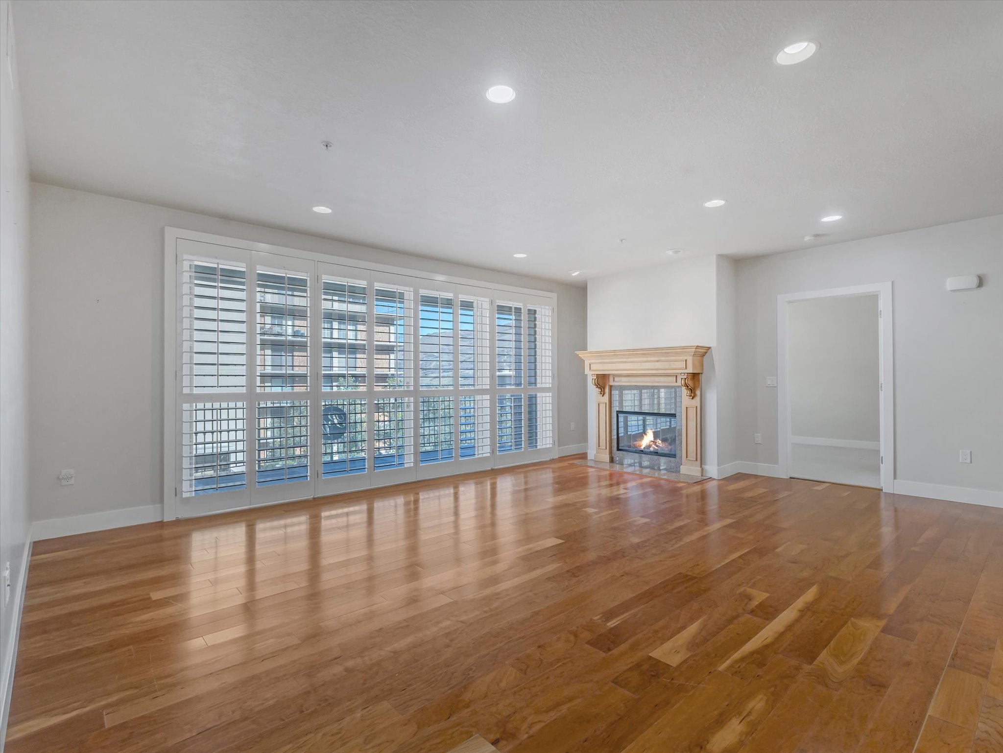Unfurnished living room featuring wood finished floors, a tiled fireplace, and recessed lighting