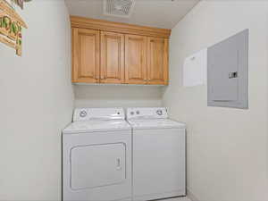 Laundry room featuring electric panel, cabinet space, and independent washer and dryer/