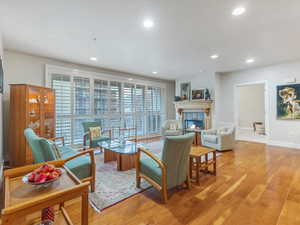 Living room with light wood-style floors, a tile fireplace, and recessed lighting/