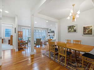 Dining area featuring light wood-type flooring, suspended lighting, and a fireplace