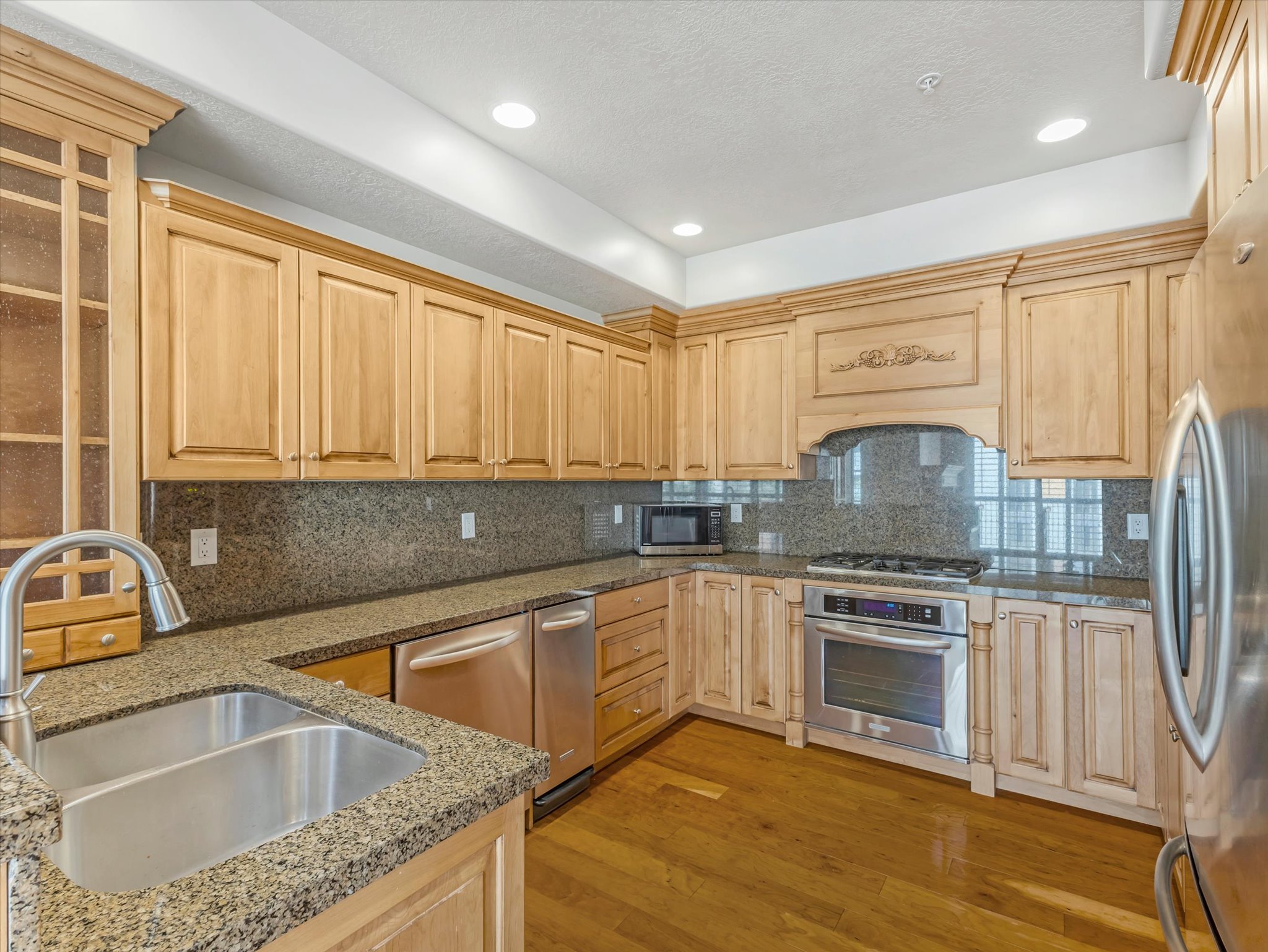 Kitchen with light wood finished floors, stainless steel appliances, decorative backsplash, light wood finish cabinetry, and recessed lighting