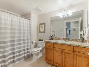 Guest Bathroom with full bath featuring curtained shower, vanity, light tile patterned floors, hanging lights, and custom cabinets.